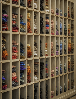 Dans des étagères de chêne clair, les gants aux couleurs chatoyantes s'empilent, créant de vibrantes harmonies...